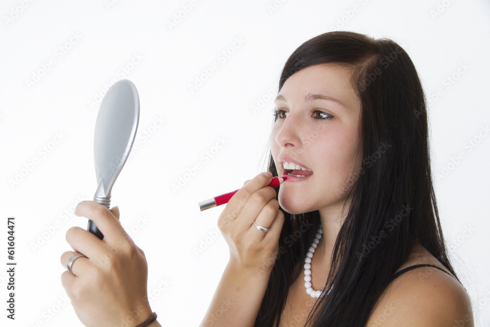 Teenager schminkt sich vor einem Handspiegel - Hintergrund weiß. Teenager schminkt sich vor einem Handspiegel - Hintergrund weiß.