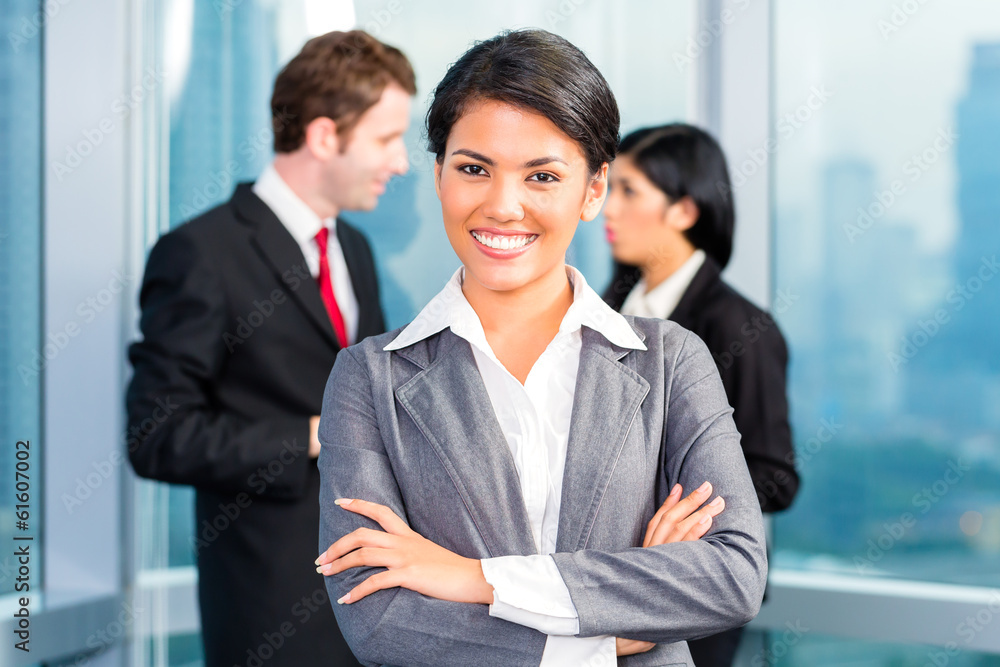 Asian business team in office, woman in front with skyline Asian business team in office, woman in front with skyline