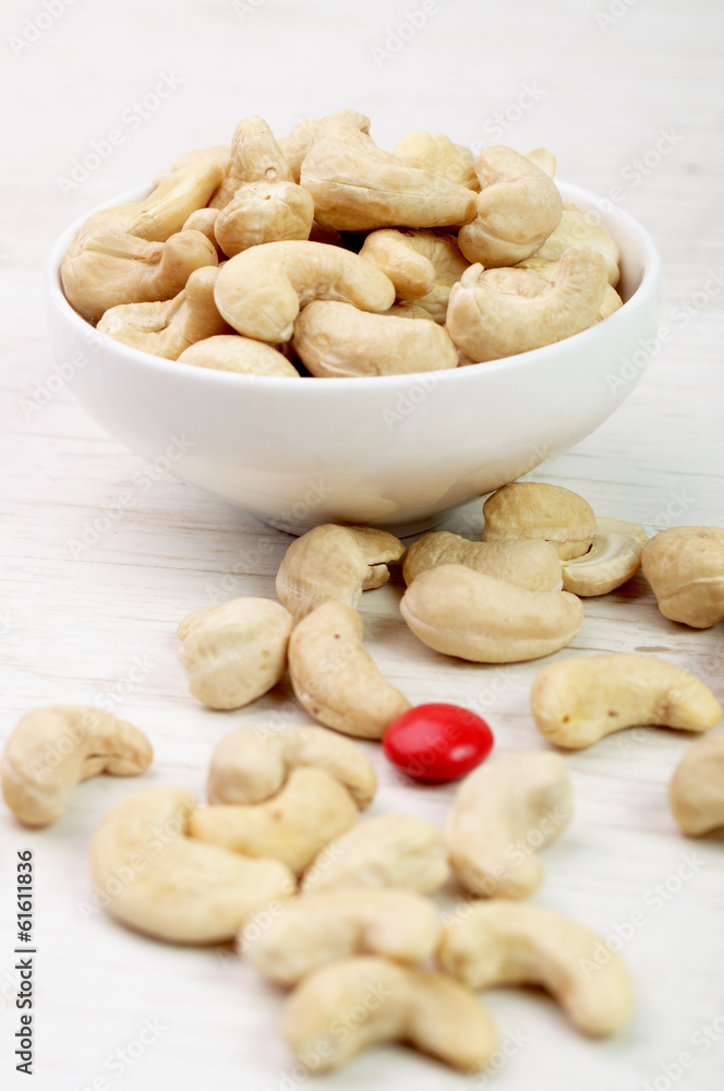 Cashew nuts in a bowl and one red candy Cashew nuts in a bowl and one red candy