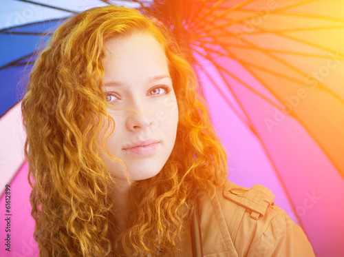 Redhead girl and colorful umbrella as background.
