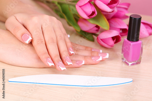 Beautiful woman hands with french manicure and flowers