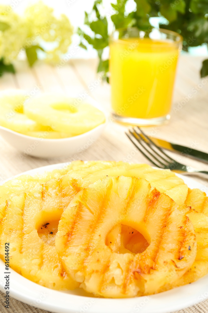 Juicy grilled pineapple on plate on table close-up