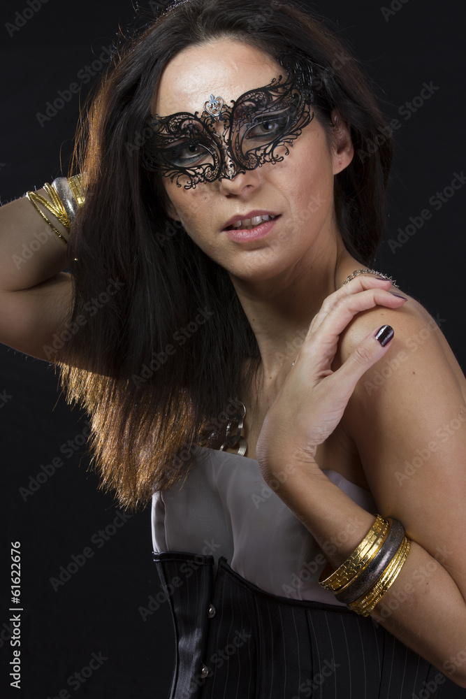 Beautiful young woman in mysterious black Venetian mask. Fashion