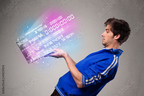 Casual man holding laptop with exploding data and numbers