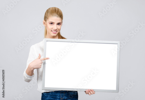 Young student girl smiling and pointing to a blank white board.