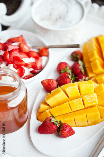 Healthy breakfast with mango, strawberry, honey and cereal