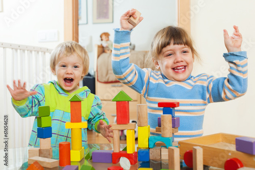 Two happy children playing with  blocks  in home