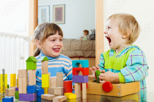 Emotional happy siblings playing with wooden toys