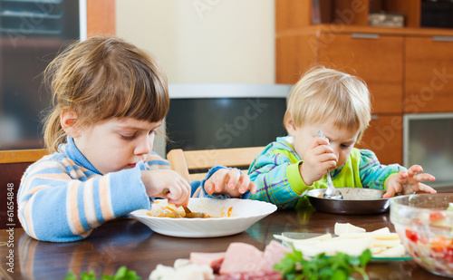 Baby girls eating at wooden table