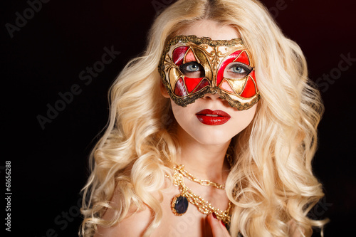 Portrait of a blonde in a carnival mask on a dark background