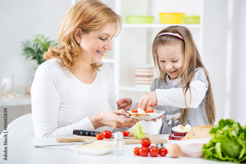 Grandmother and her granddaughter making Sandwich.