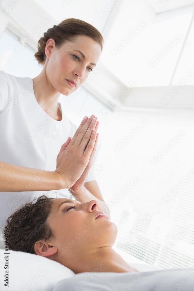 Therapist giving Reiki treatment to woman at spa Therapist giving Reiki treatment to woman at spa