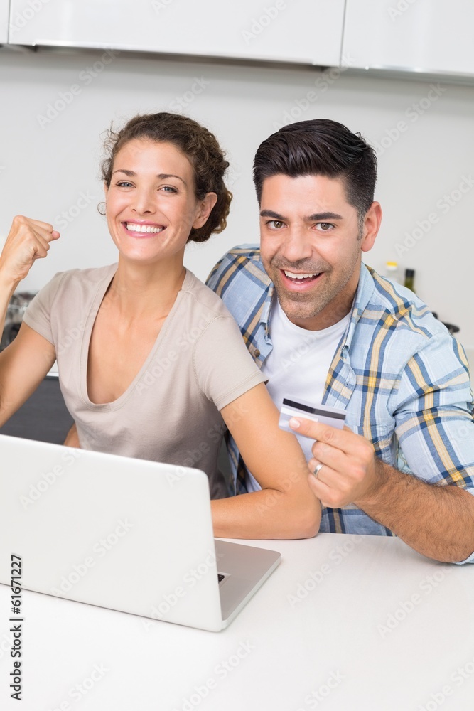 Excited couple using laptop together to shop online Excited couple using laptop together to shop online