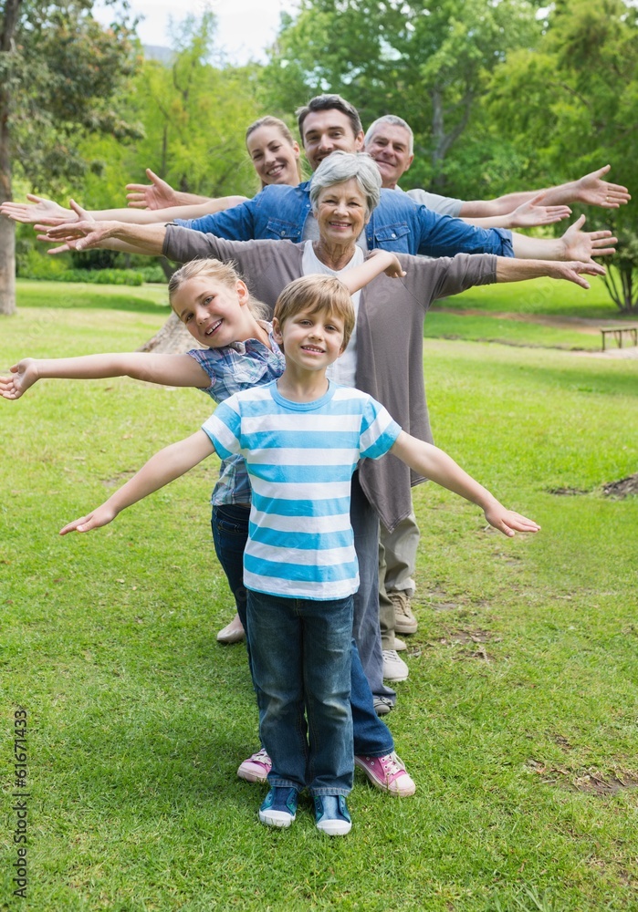 Fototapeta premium Extended family standing in row with arms outstretched at park