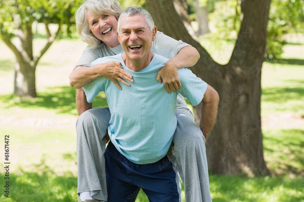 Fototapeta premium Cheerful mature man carrying woman at park
