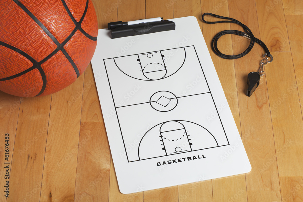 Fototapeta premium A basketball with coach's clipboard and whistle on a wooden gymn