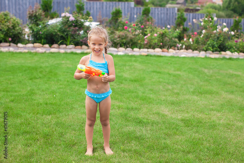 Little adorable girl playing with water gun outdoor in sunny