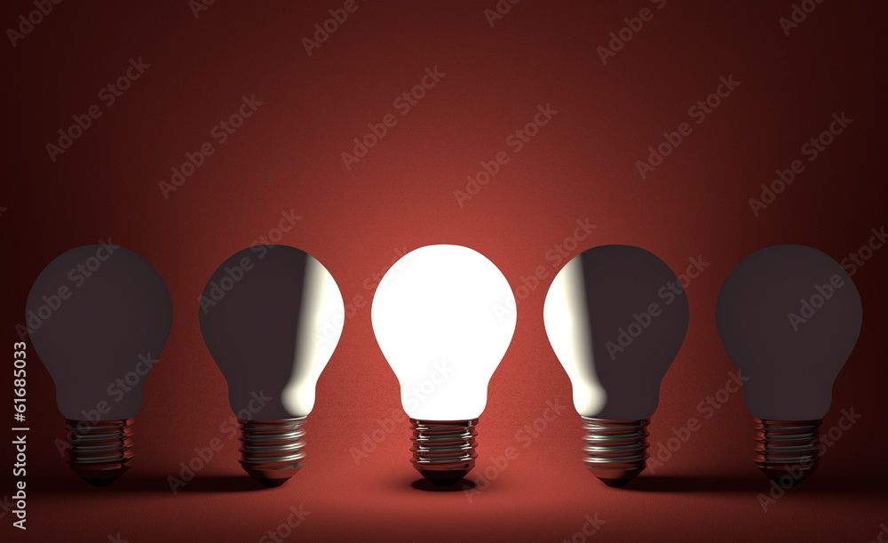Glowing light bulb in row of switched off ones on red Glowing light bulb in row of switched off ones on red