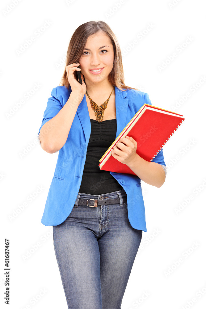 Young woman holding notebooks and talking on cell phone Young woman holding notebooks and talking on cell phone