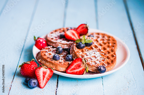 Whole grain waffles with berries on blue wooden background