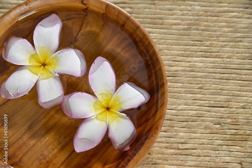 frangipani flower in wooden bowl on Brown straw mat