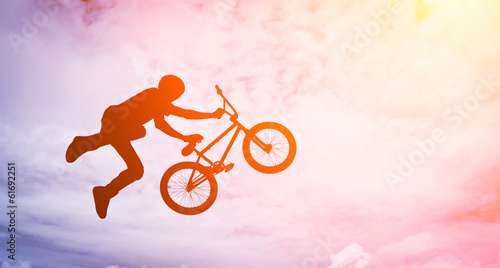 Photo Man doing an jump with a bmx bike against sunshine sky.