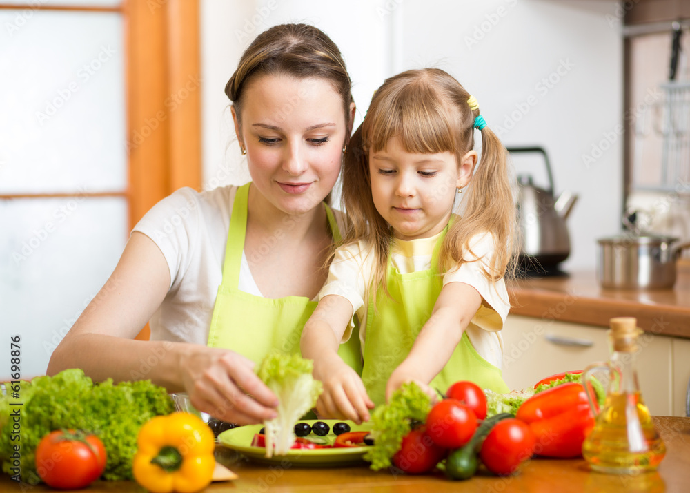 Young mother and her kid making vegetable salad Young mother and her kid making vegetable salad