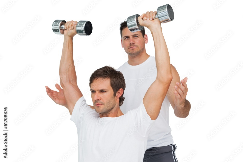 Male trainer assisting man with dumbbells Male trainer assisting man with dumbbells