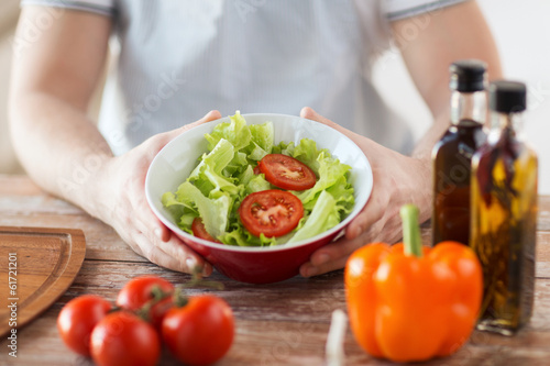 close of male hand holding a bowl with salad