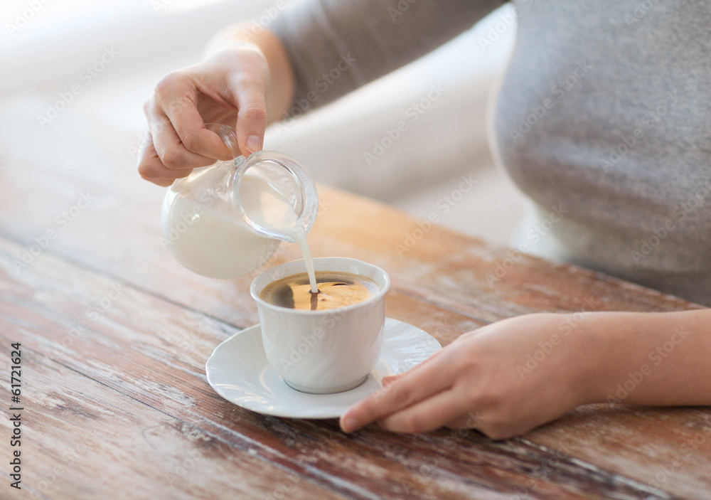 close up of female pouring milk into coffee close up of female pouring milk into coffee