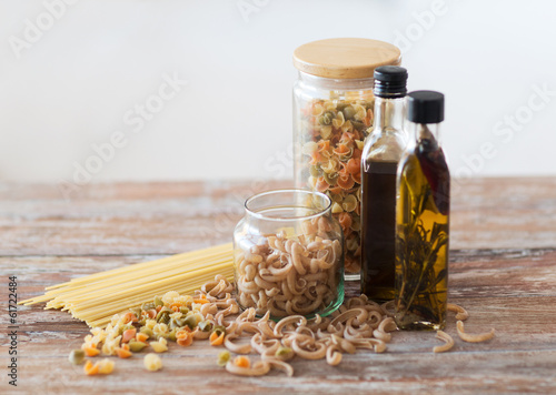 close up of two olive oil bottles and pasta in jar