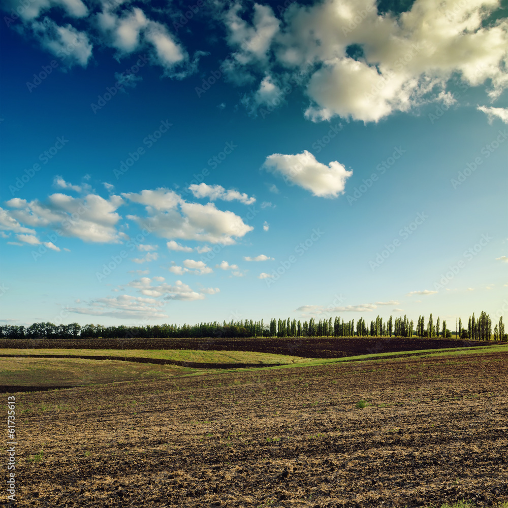 dark sky with clouds over plowed field dark sky with clouds over plowed field