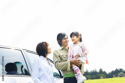 parents and daughter standing in front of car in prairie