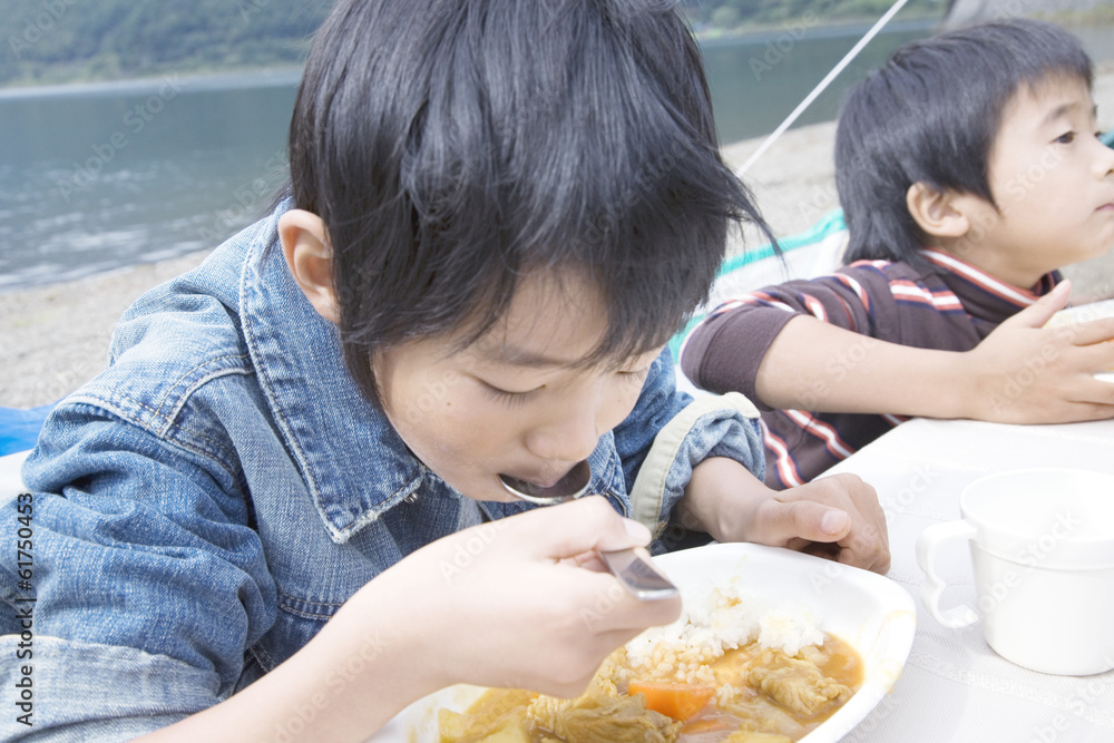 boy eating curry and rice by lakeside boy eating curry and rice by lakeside
