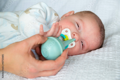Fotografie Mother using bulb syringe to clean baby's nose