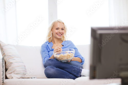 young girl with popcorn watching movie at home