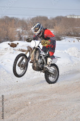 Motocross rider on a motorcycle driving on winter road holding u