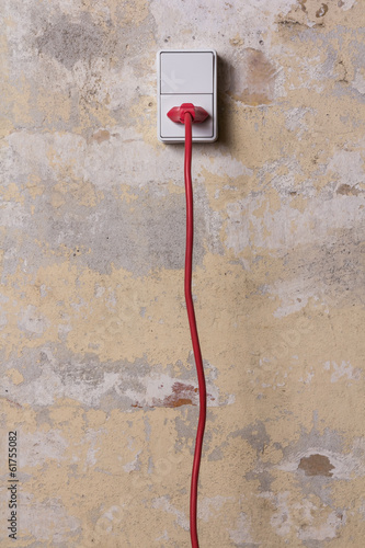 Socket with red wire on grungy wall
