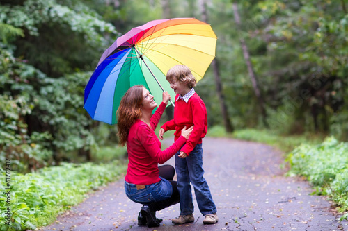 Mother and son laughing under a colorful umbrella