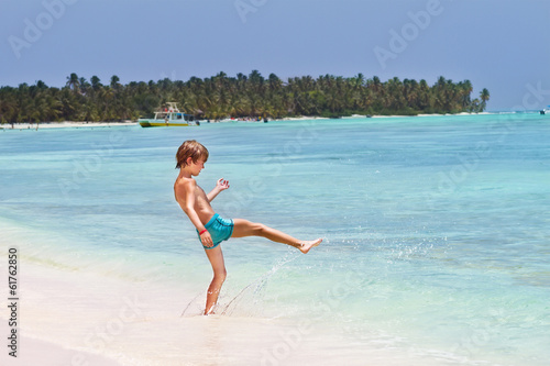 Little boy playing in the ocean on a tropical beach