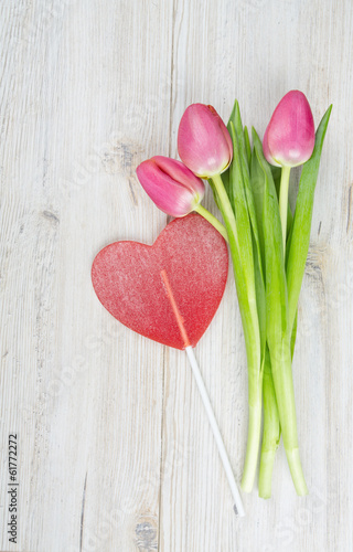 three pink tulips tied with a ribbon and valentine candy