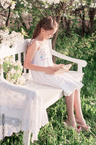 smiling girl with open book is sitting on the wooden bench in sp © Maya Kruchancova
