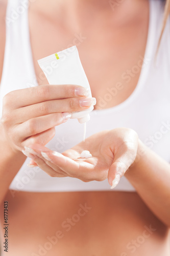 Beautiful young woman applying hand cream.
