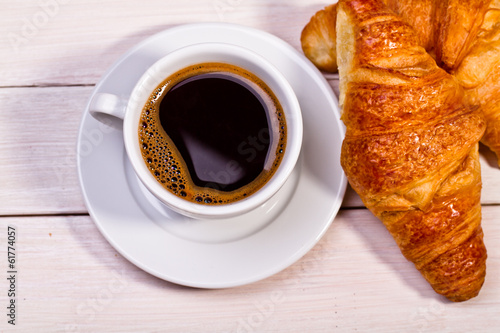 Fototapeta Naklejka Na Ścianę i Meble -  Coffee cup with a croissant isolated on wooden table 