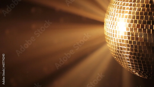 Shiny disco ball with golden reflection and rays in haze