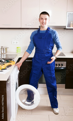 Service worker repairing washing machine © JackF