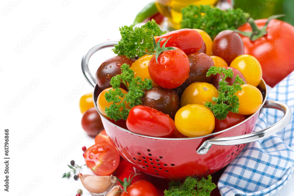 Assorted cherry tomatoes and greens in a colander, isolated Assorted cherry tomatoes and greens in a colander, isolated