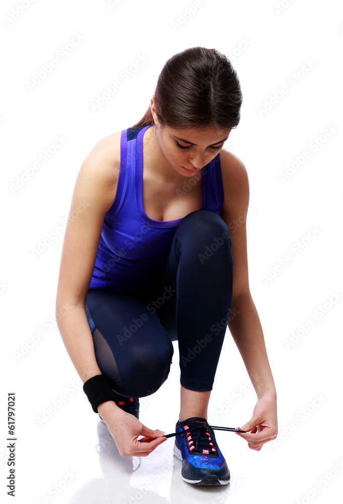 Young sport woman tying shoelaces isolated on white background Young sport woman tying shoelaces isolated on white background
