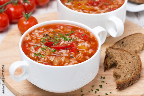 tomato soup with rice, vegetables and herbs on wooden table