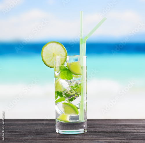 Glass of mojito cocktail on a beach